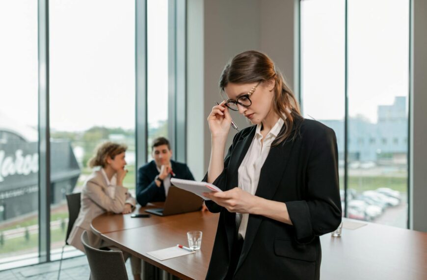 Confident woman reviewing notes leading a business meeting in a modern office setting.