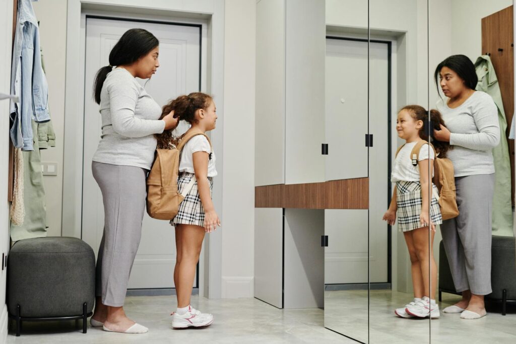 A mother and daughter preparing for school in front of a mirror, showcasing morning routines.