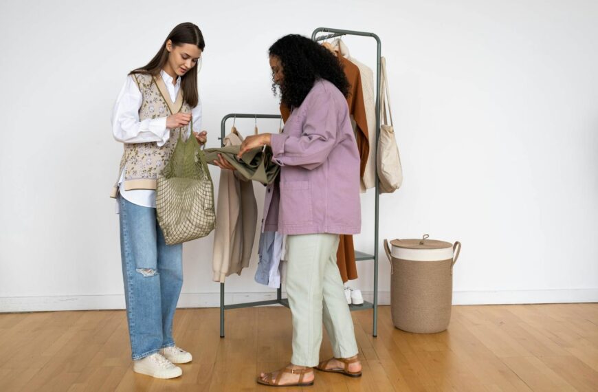 Two women shopping and discussing clothing together indoors with a fashionable wardrobe setup.