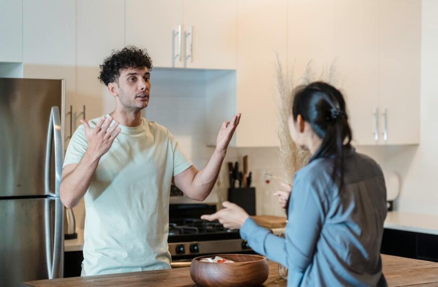 A couple in a tense conversation in a modern kitchen, expressing emotions.