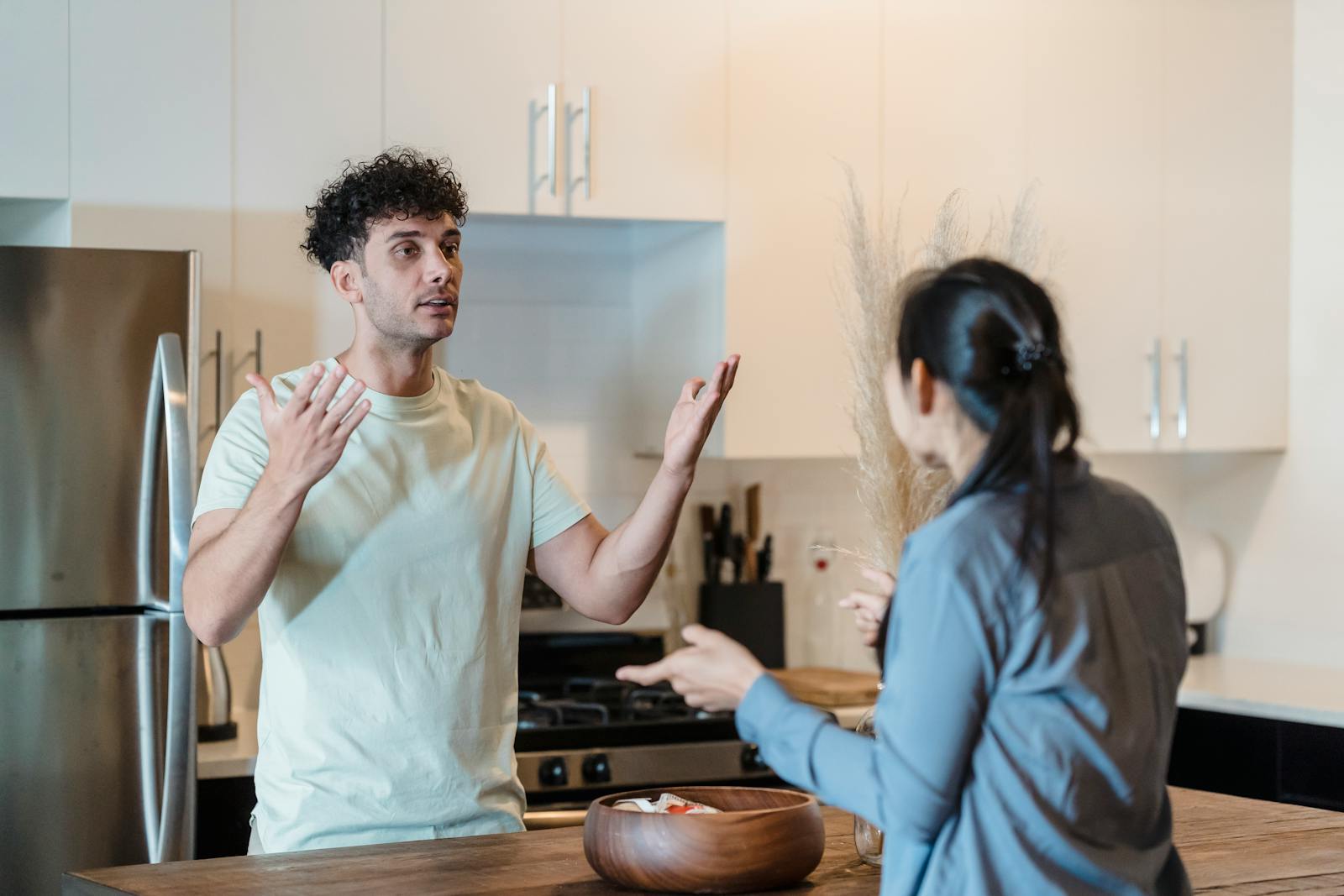 A couple in a tense conversation in a modern kitchen, expressing emotions.