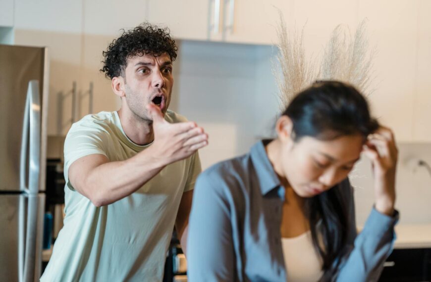 A stressed couple arguing in a modern kitchen, highlighting relationship issues.