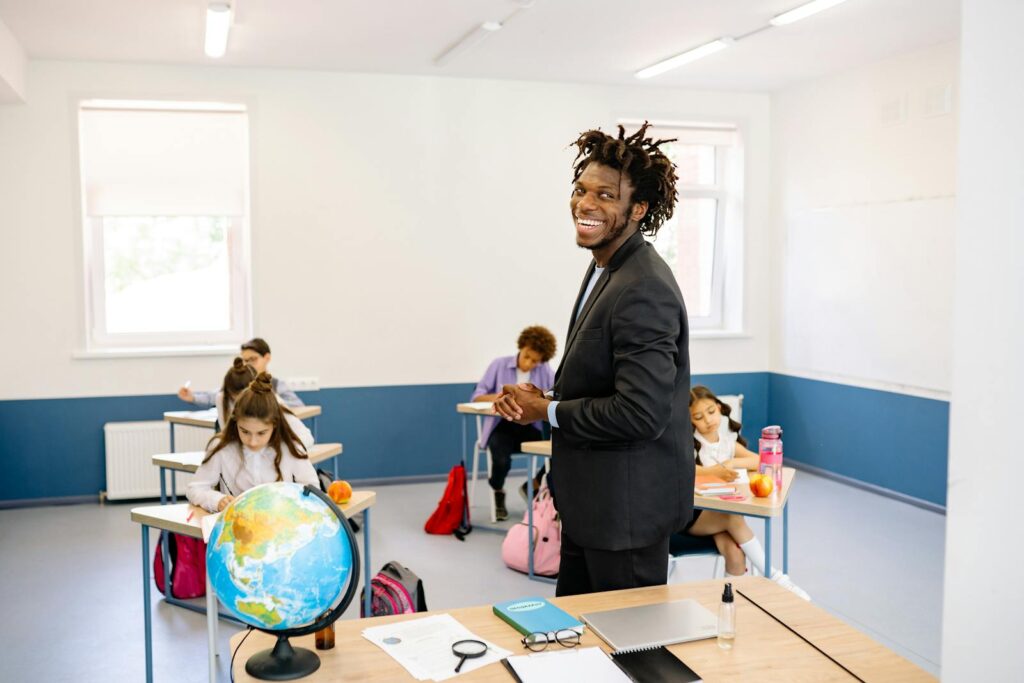 Teacher engaging with students in a bright classroom, promoting a positive learning environment.
