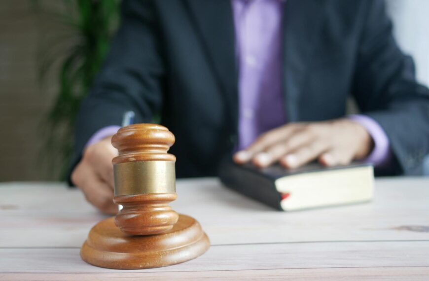 A wooden gavel and legal book represent justice in a court setting, emphasizing order and legal authority.