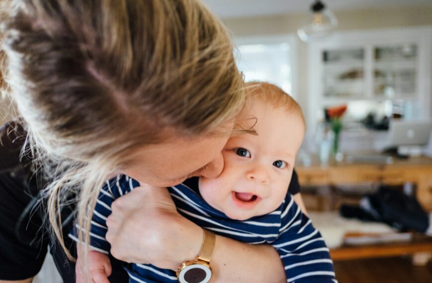 woman carrying baby in striped shirt