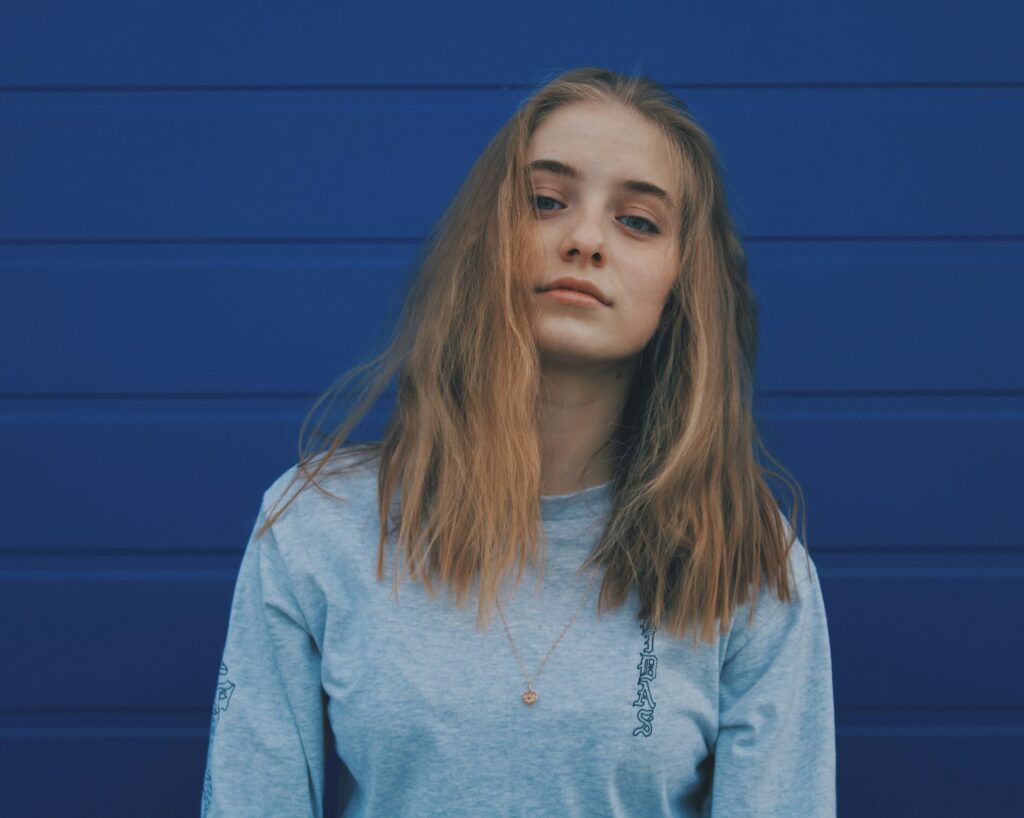 a woman with long hair standing in front of a blue wall
