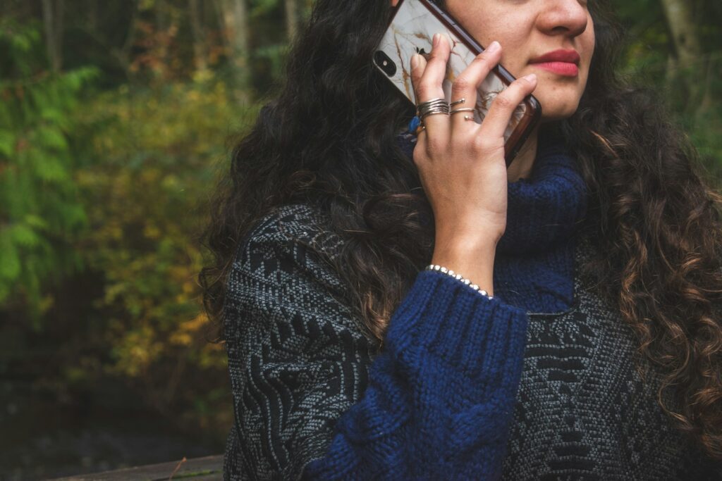 woman in blue sweater holding smartphone