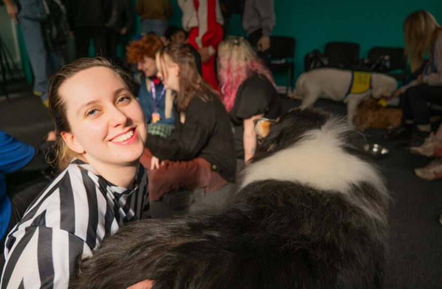 A woman standing next to a black and white dog