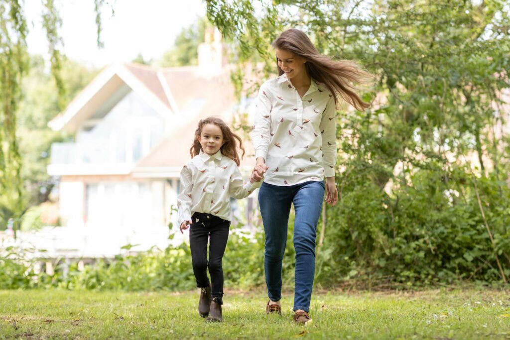 a woman and a little girl walking in the grass