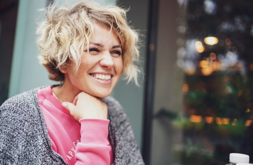 smiling girl in pink shirt and gray cardigan