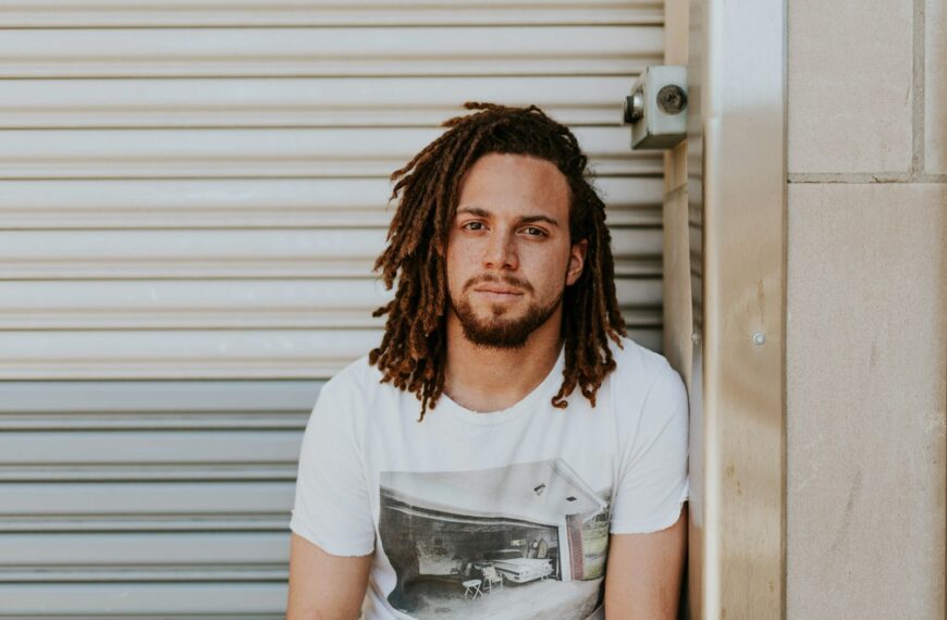 man sitting near gray steel roller shutters during daytime