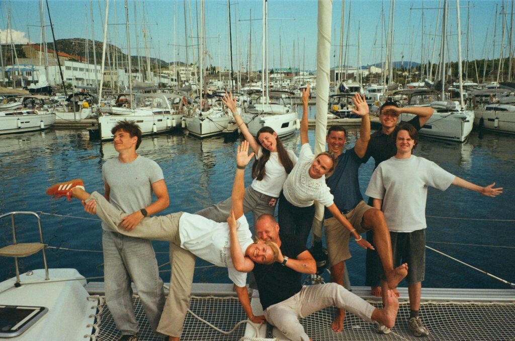 Group of friends posing on a sailboat dock.