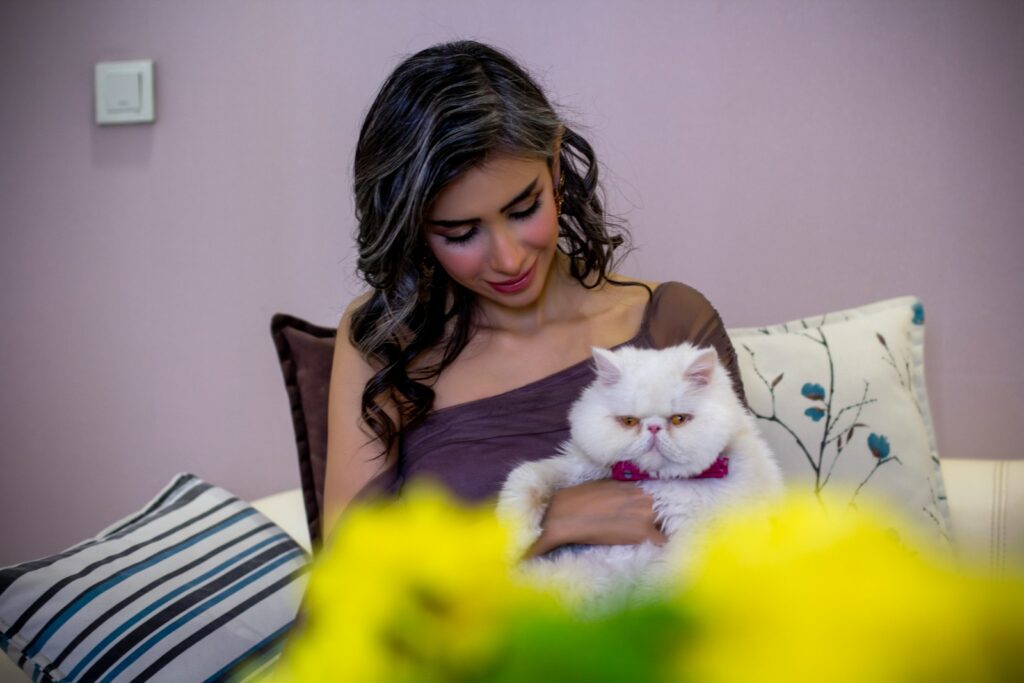 A woman cuddles a white persian cat.