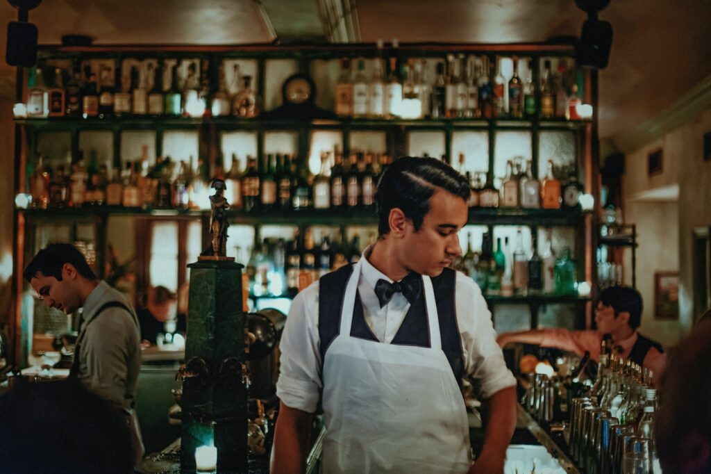 A man in an apron standing in front of a bar