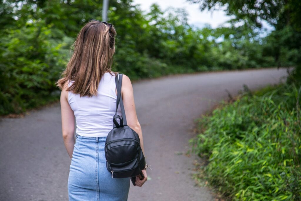 a woman walking down a road with a backpack on her back