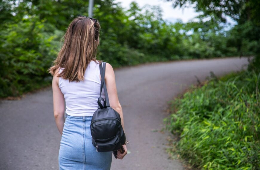 a woman walking down a road with a backpack on her back