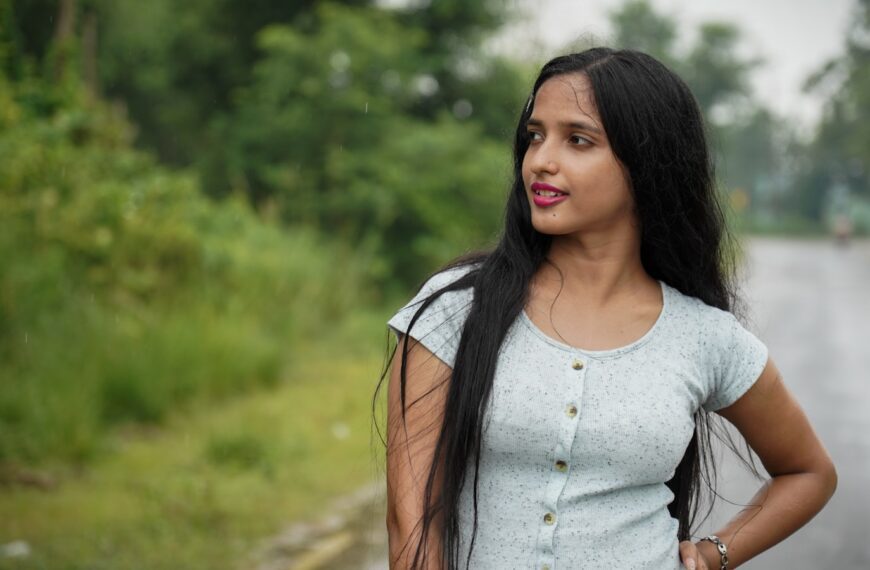 woman in white scoop neck shirt standing on green grass field during daytime