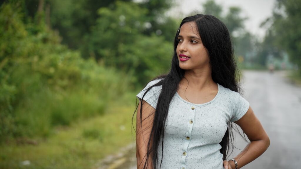 woman in white scoop neck shirt standing on green grass field during daytime