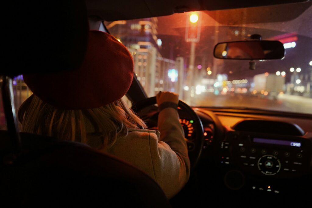 a woman driving a car at night on a city street