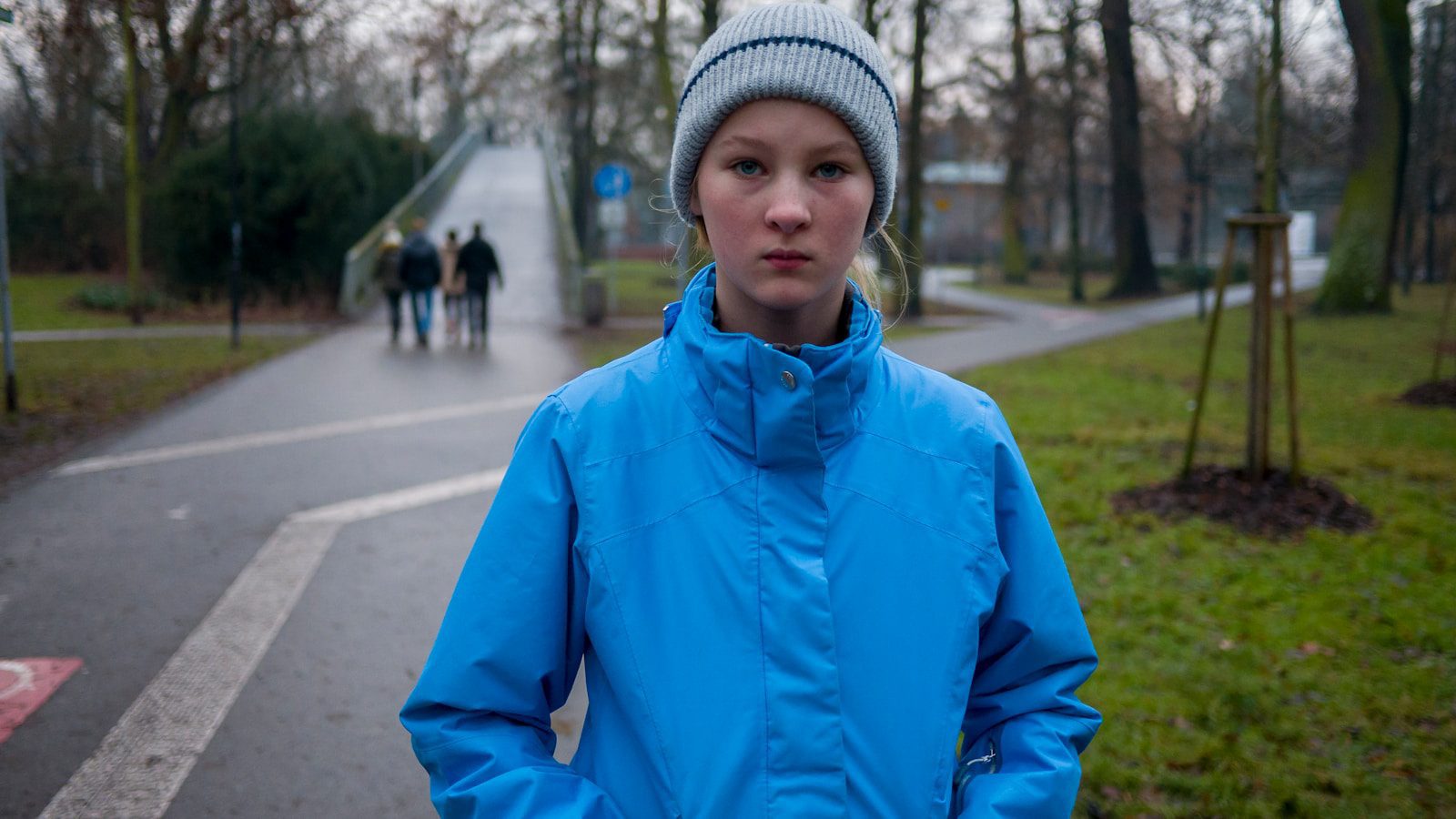 boy in blue jacket and gray knit cap standing on sidewalk during daytime