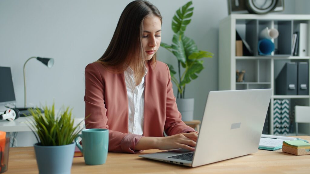 Woman working on laptop at office desk.