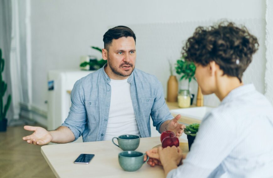 a man sitting at a table talking to a woman