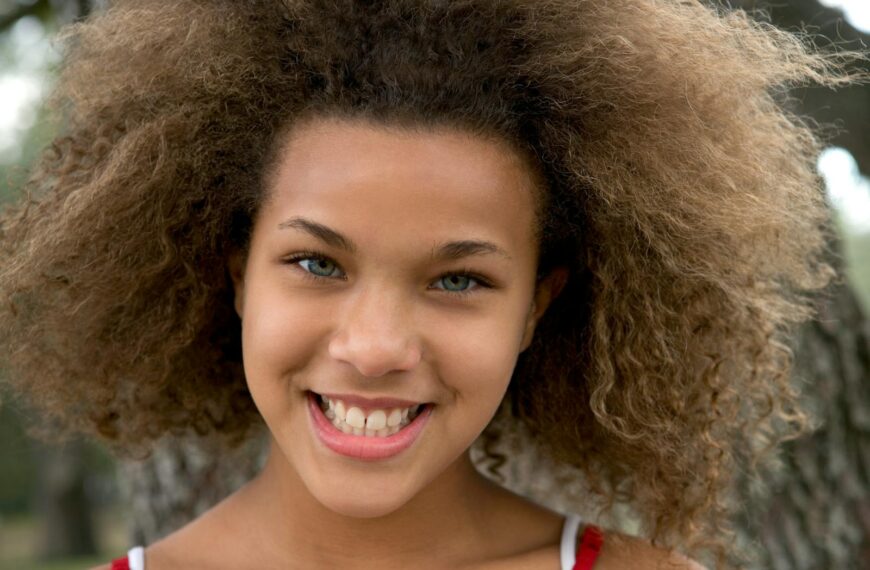 A smiling teenager with beautiful natural curls enjoying the day outdoors, embodying vibrant youthfulness.