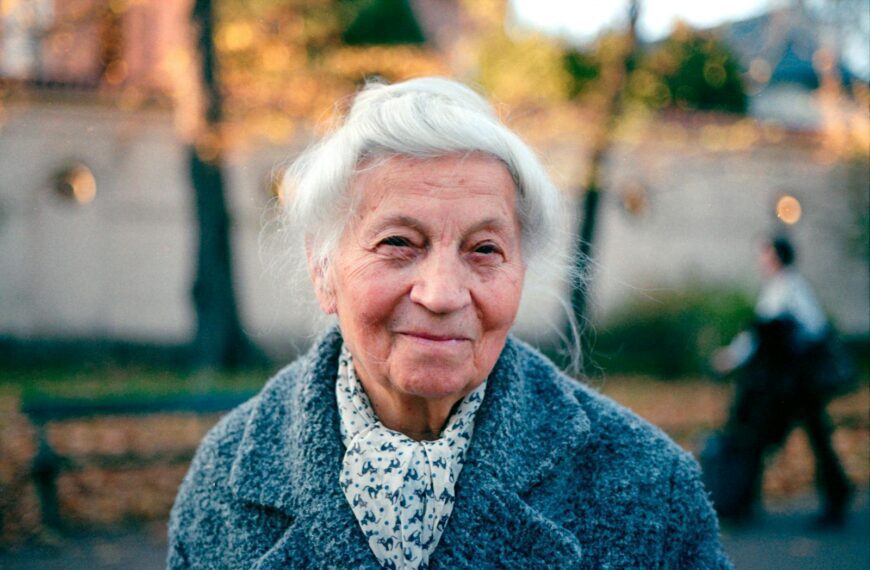 Portrait of a smiling elderly woman outdoors in Kraków during fall.