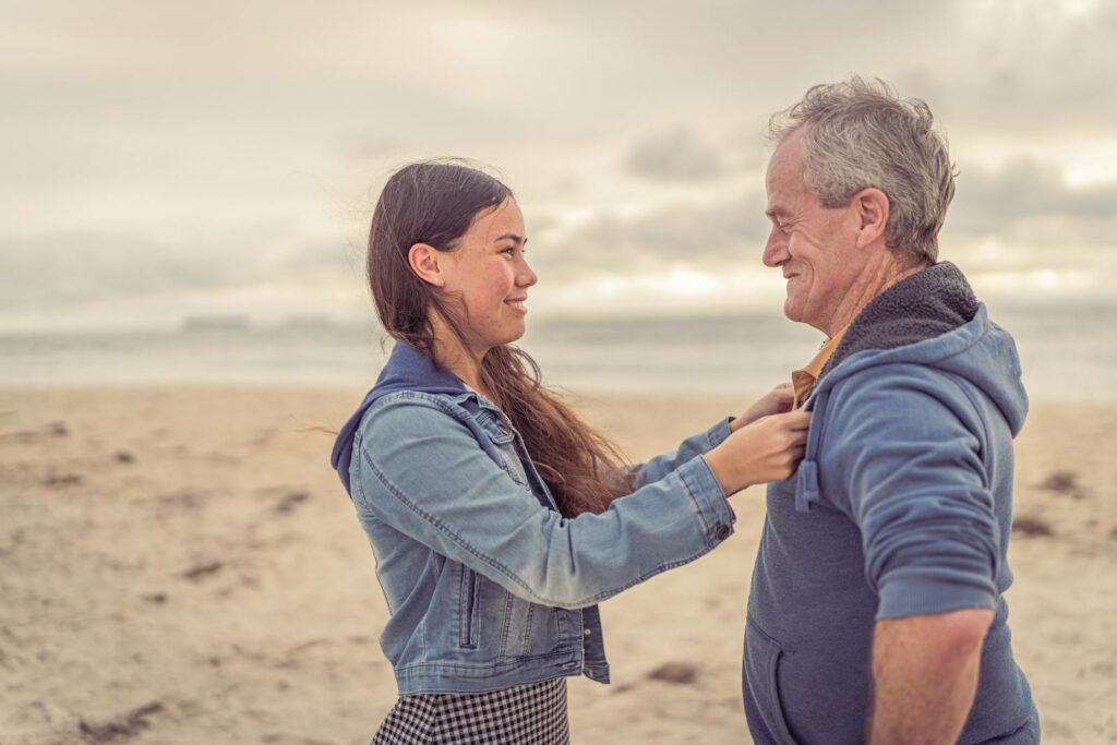 A father and daughter share a joyful moment at the beach, embracing family bonds.