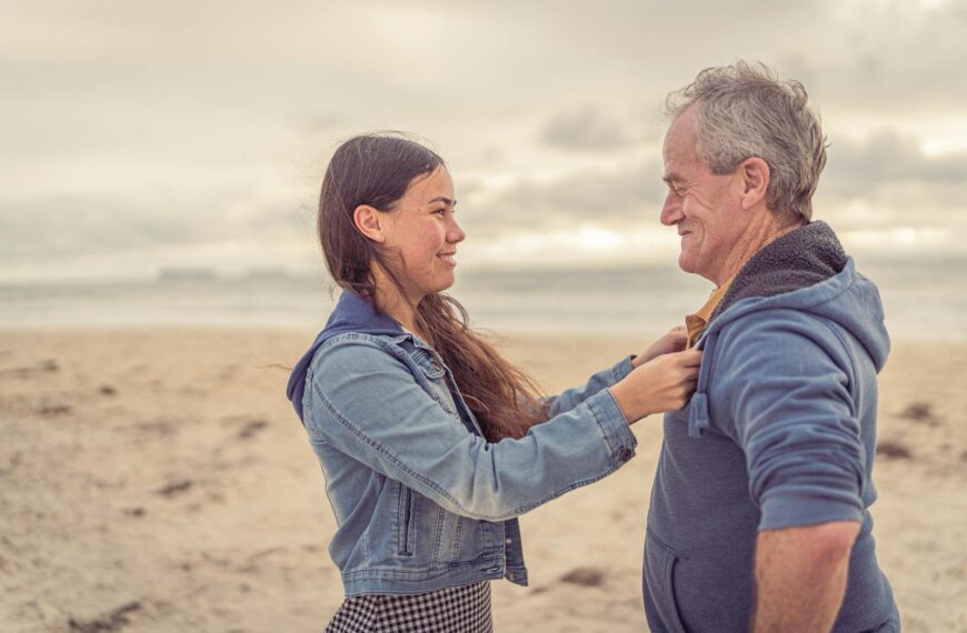 A father and daughter share a joyful moment at the beach, embracing family bonds.