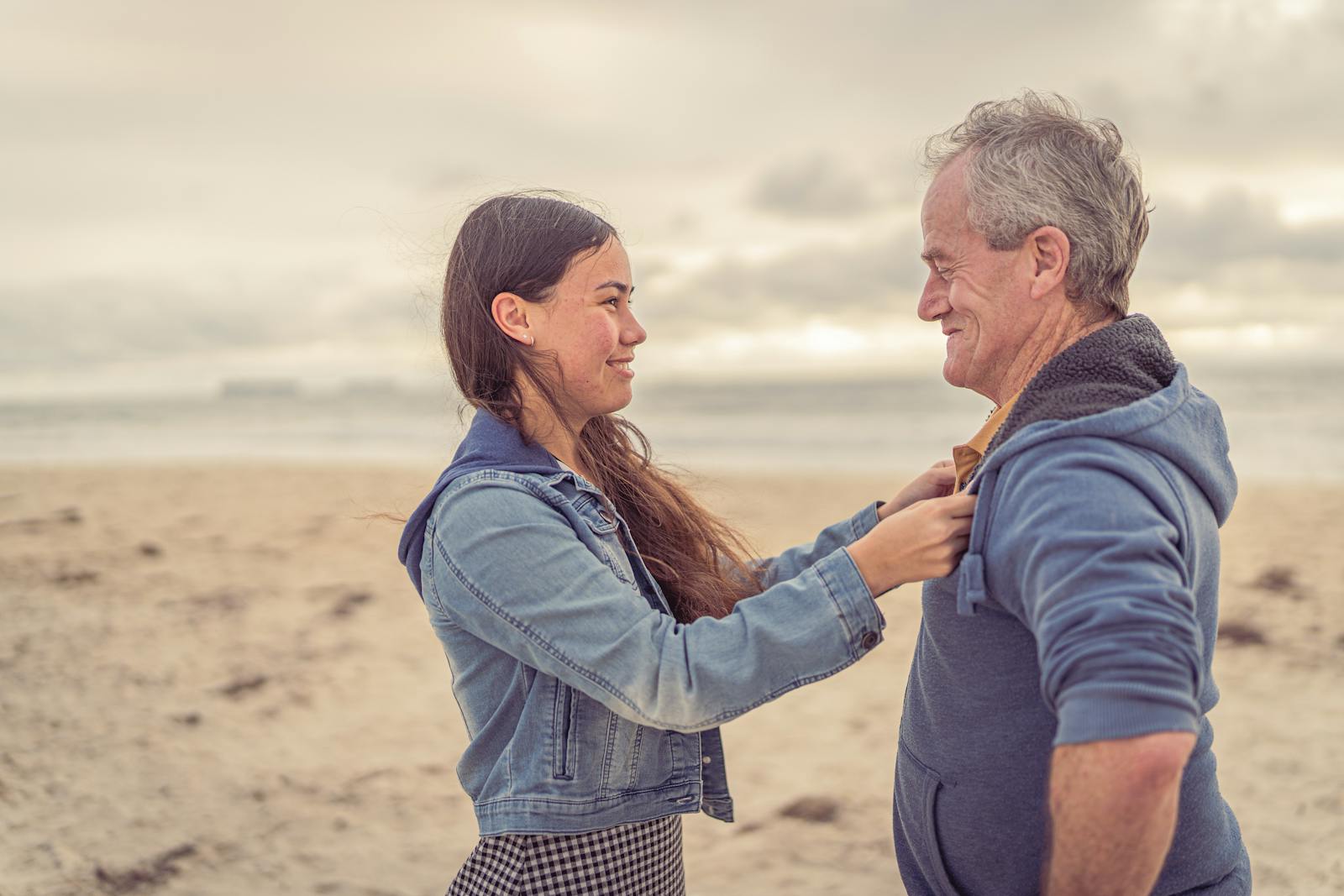 A father and daughter share a joyful moment at the beach, embracing family bonds.