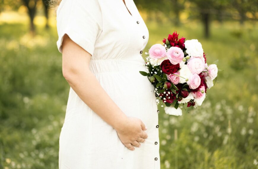 Pregnant woman holds flowers.