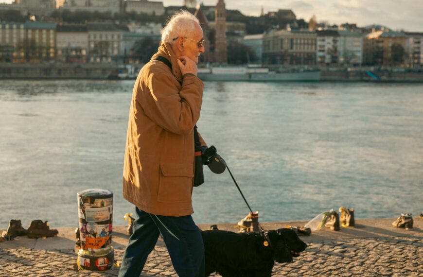 Elderly man walking his dog along the Danube River in Budapest, Hungary.