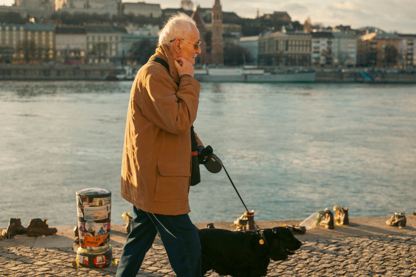 Elderly man walking his dog along the Danube River in Budapest, Hungary.