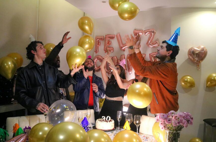 Vibrant birthday party with friends celebrating amidst balloons and festive decorations.