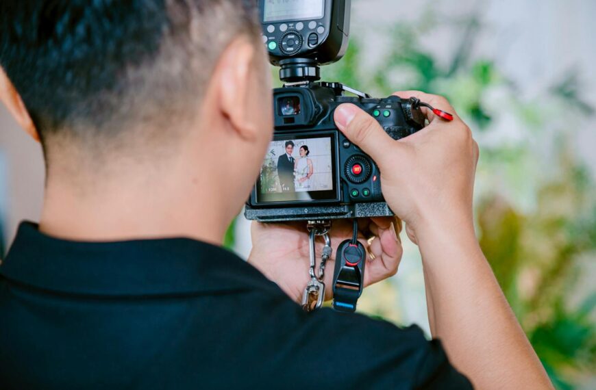 A photographer focuses on capturing a wedding couple using a digital camera during a ceremony.