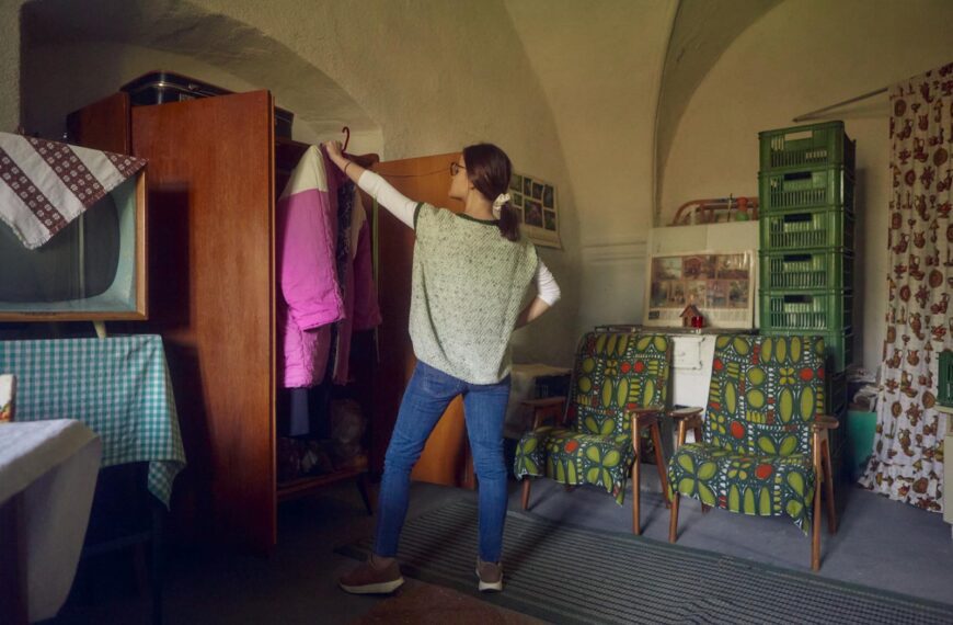 A woman organizing her wardrobe in a vintage-style room with retro furniture and decor.