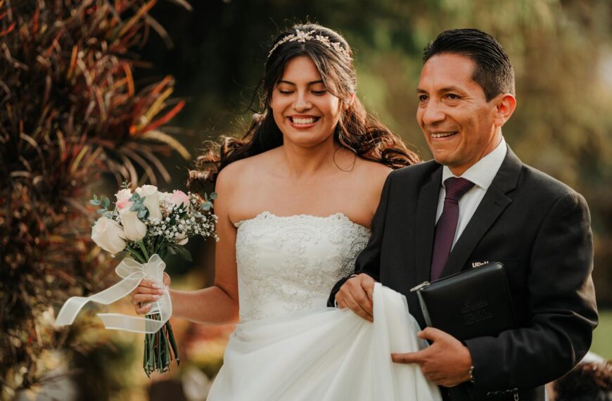 A bride joyfully walks with her father during a wedding ceremony outdoors.