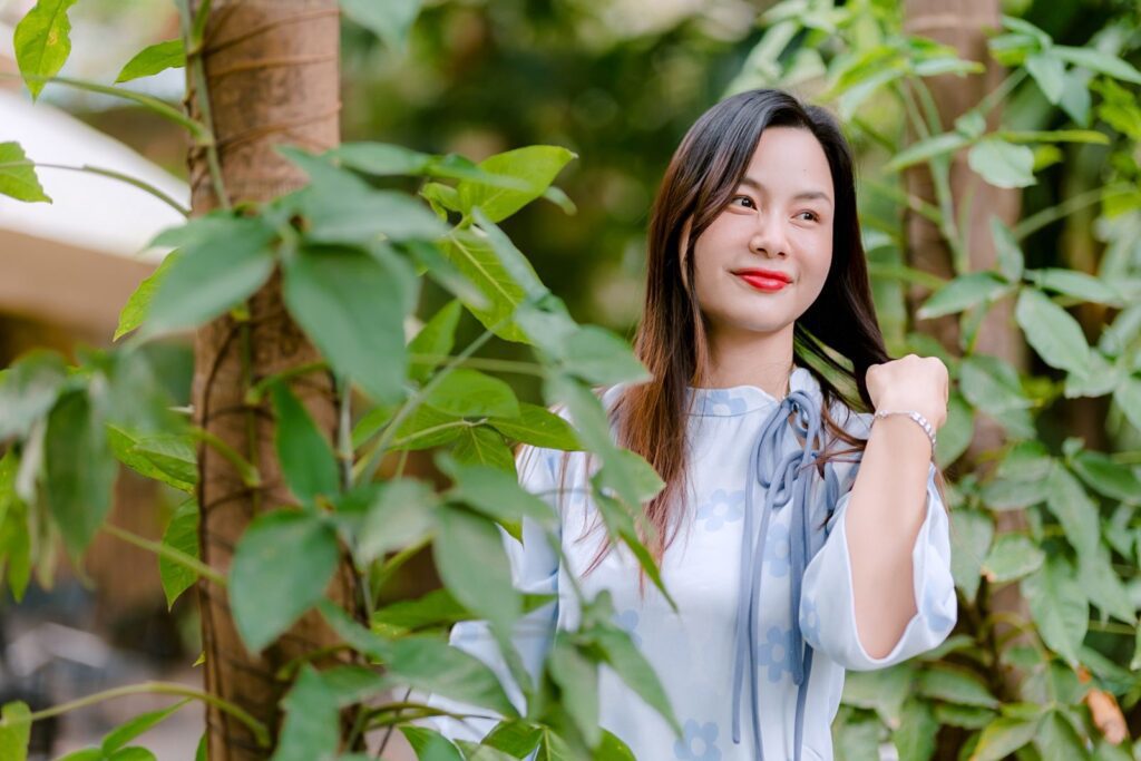 Portrait of a smiling woman outdoors amidst lush green foliage, embodying natural beauty.