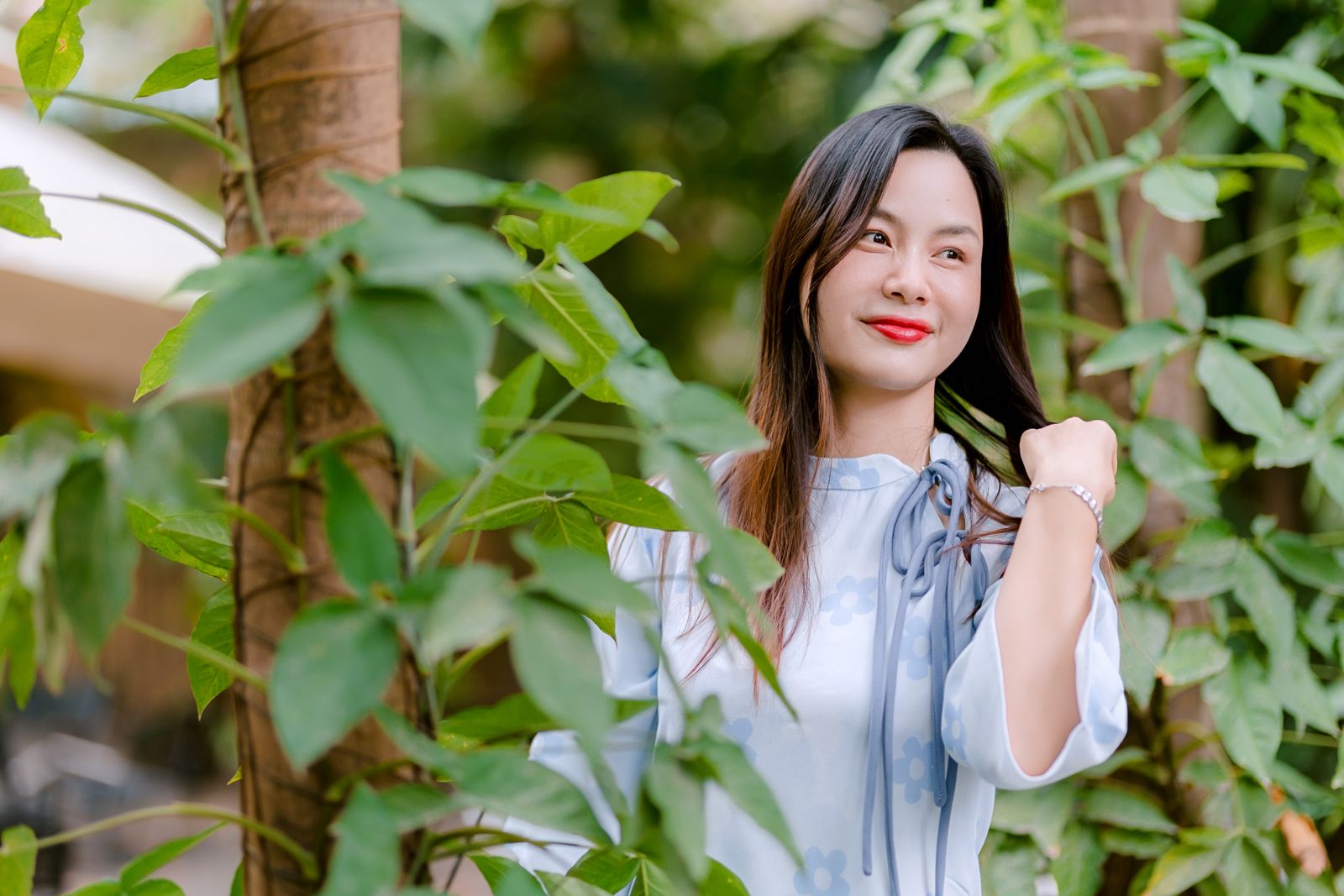 Portrait of a smiling woman outdoors amidst lush green foliage, embodying natural beauty.