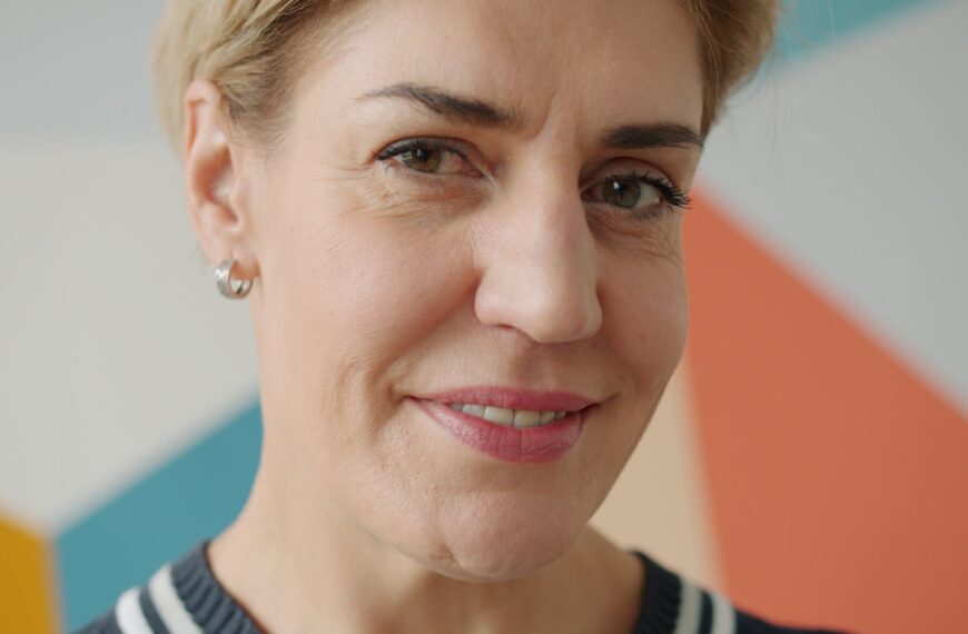 Close-up of a smiling mature woman in front of a colorful geometric background.