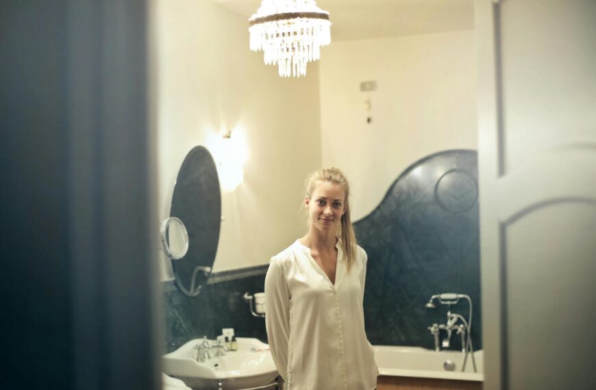 Portrait of a smiling woman in a stylish bathroom setting, showcasing luxurious decor and ambient lighting.