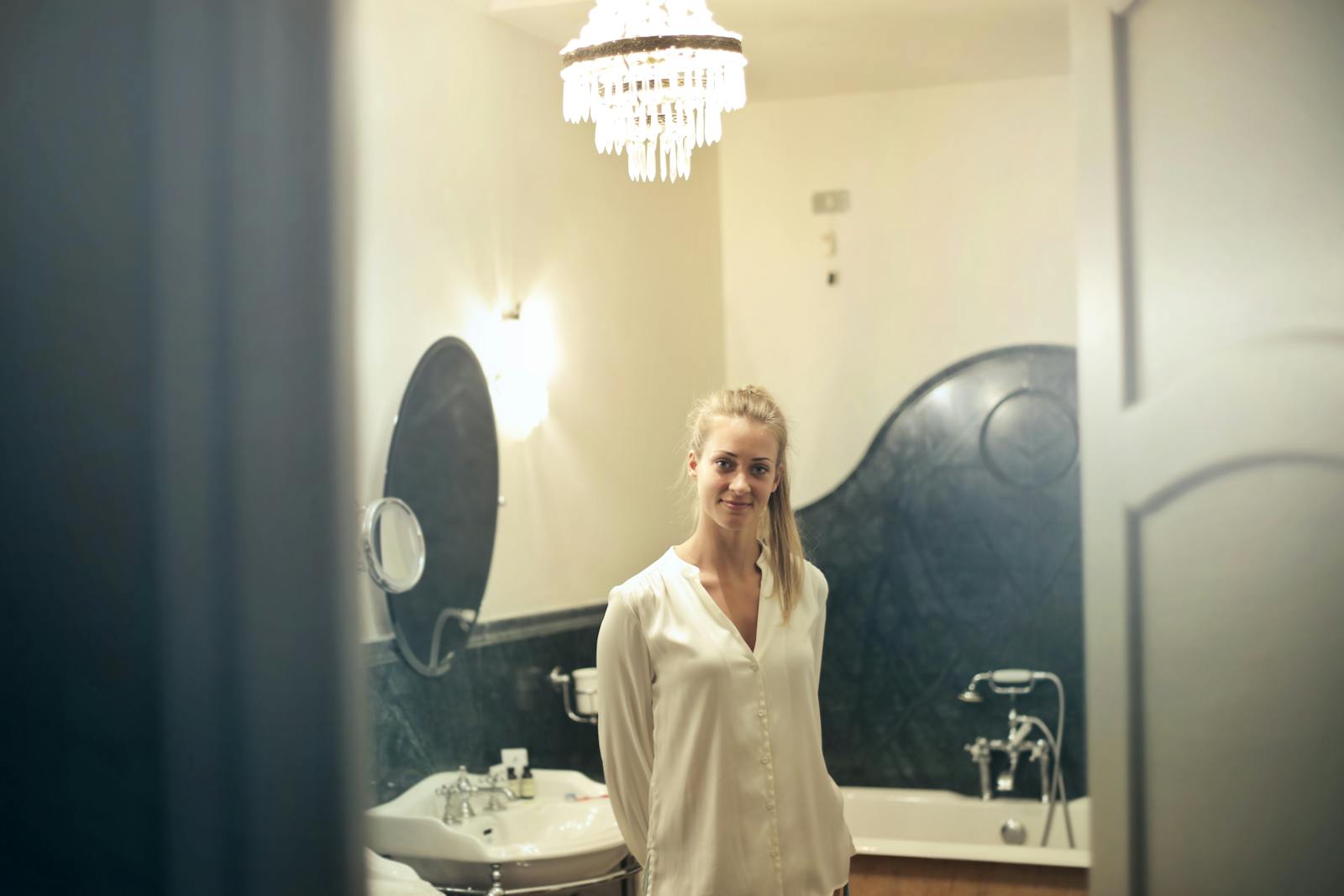 Portrait of a smiling woman in a stylish bathroom setting, showcasing luxurious decor and ambient lighting.