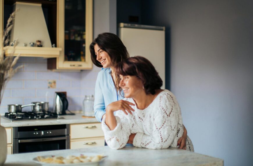 A mother and daughter share a moment of joy and togetherness in their cozy kitchen.