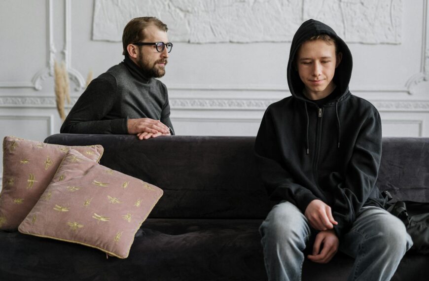 Teen in black hoodie during a therapy session in a calm indoor setting.
