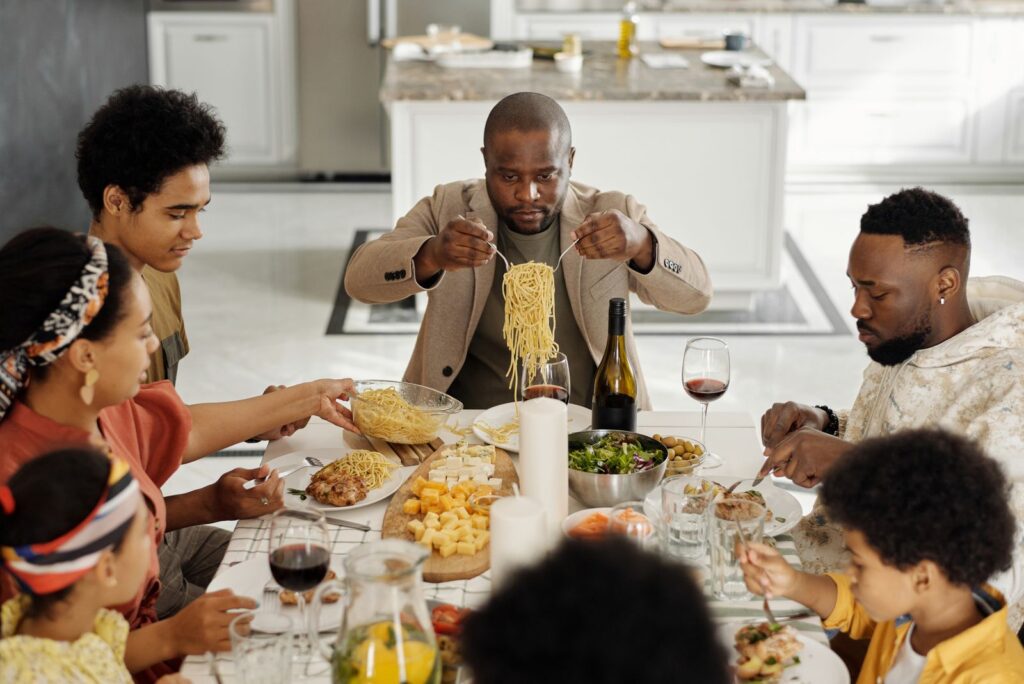 A warm family gathering enjoying dinner together with wine and pasta.