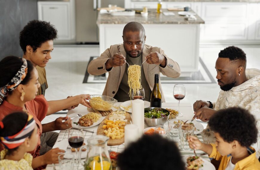 A warm family gathering enjoying dinner together with wine and pasta.
