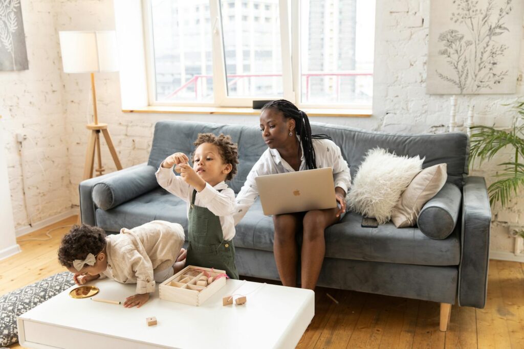 Mother and children spending quality time at home, playing and using a laptop.