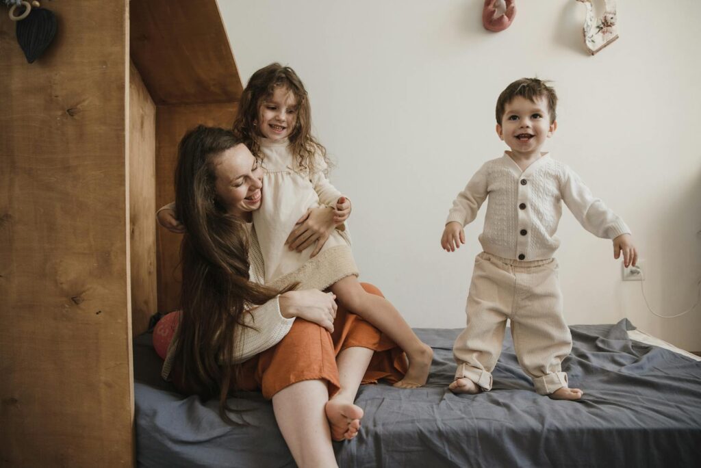 A joyful mother spending quality time with her children on a bed, creating precious memories.