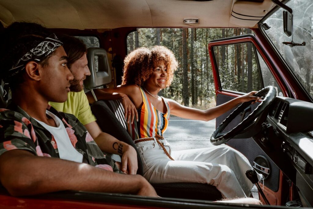 Young friends on a joyful summer road trip in a vintage car through the woods.